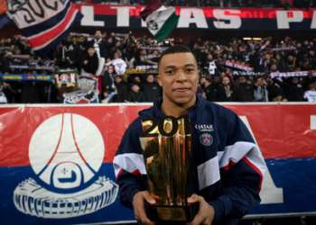 Paris Saint-Germain's French forward Kylian Mbappe poses with a trophy in front of supporters at the end of a ceremony after he became Paris Saint-Germain's all-time top scorer with his 201st goal for the club in their 4-2 win in the French L1 football match against FC Nantes at The Parc des Princes Stadium in Paris on March 4, 2023. (Photo by FRANCK FIFE / POOL / AFP)
