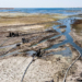 This picture taken on July 27, 2021 shows an aerial view of water pumps drawing water from the Lake Assad reservoir (unseen), in the village of al-Tuwayhinah near the Tabqa Dam along the Euphrates river in Raqqa province in eastern Syria. - Aid groups and engineers are warning of a looming humanitarian disaster in northeast Syria, where plummeting water levels at hydroelectric dams since January are threatening water and power cutoffs for millions amidst the coronavirus pandemic and economic crisis. Many in the Kurdish-held area are accusing neighbour and archfoe Turkey of weaponising water by tightening the tap upstream. (Photo by Delil SOULEIMAN / AFP)