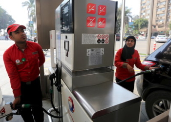 A female employee works alongside a male colleague at a petrol station in Cairo, Egypt, February 24, 2016. A petrol station in the Egyptian capital Cairo hires women to work as attendants - until now, petrol stations were staffed almost exclusively by men. Picture taken February 24, 2016. REUTERS/Mohamed Abd El Ghany      TPX IMAGES OF THE DAY