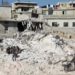 People sit on the rubble of damaged buildings in the aftermath of an earthquake, in rebel-held town of Harem, Syria February 13, 2023.  REUTERS/Mahmoud Hassano