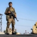 TOPSHOT - A fighter of the Syrian Democratic Forces (SDF) stands guard along a road as others deploy to impose a curfew in the town of al-Busayrah in Syria's northeastern Deir Ezzor province on September 4, 2023, during a guided media tour organised by the SDF. Days of deadly clashes between the US-backed, Kurdish-led Syrian Democratic Forces (SDF) and local fighters have rocked Deir Ezzor, threatening a fragile balance in the strategic area. (Photo by Delil SOULEIMAN / AFP) (Photo by DELIL SOULEIMAN/AFP via Getty Images)