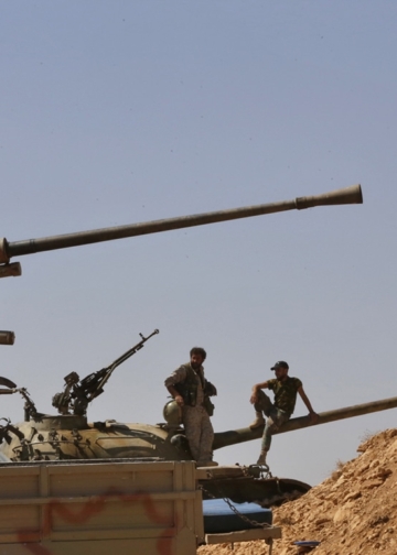 Syrian forces members stand on a tank next to vehicles waiting to transport Islamic State (IS) group members in the Qara area in Syria's Qalamoun region on August 28, 2017 as part of a deal between Hezbollah and IS fighters where the jihadists would leave to eastern Syria.
Syria's state news agency SANA, quoting a military source, confirmed Hezbollah and IS had agreed that "the remaining Daesh (IS) fighters will leave to eastern Syria". And a Lebanese military source told AFP the jihadist group would quit territory it held in eastern Lebanon.
 / AFP PHOTO / Louai Beshara        (Photo credit should read LOUAI BESHARA/AFP/Getty Images)